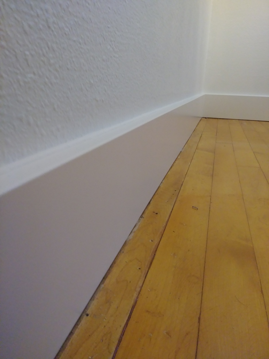Completed baseboard trim on hardwood floor, Seattle home