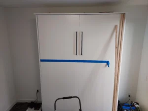 Vertical wood accent strips mid-installation on bedroom wall, Seattle