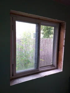 Window with dark wood frame before casing replacement, Seattle