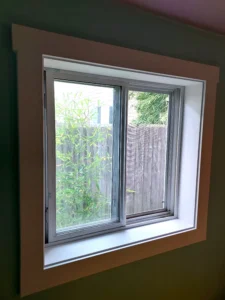 Window with new dark wood casing and trim installed, Seattle