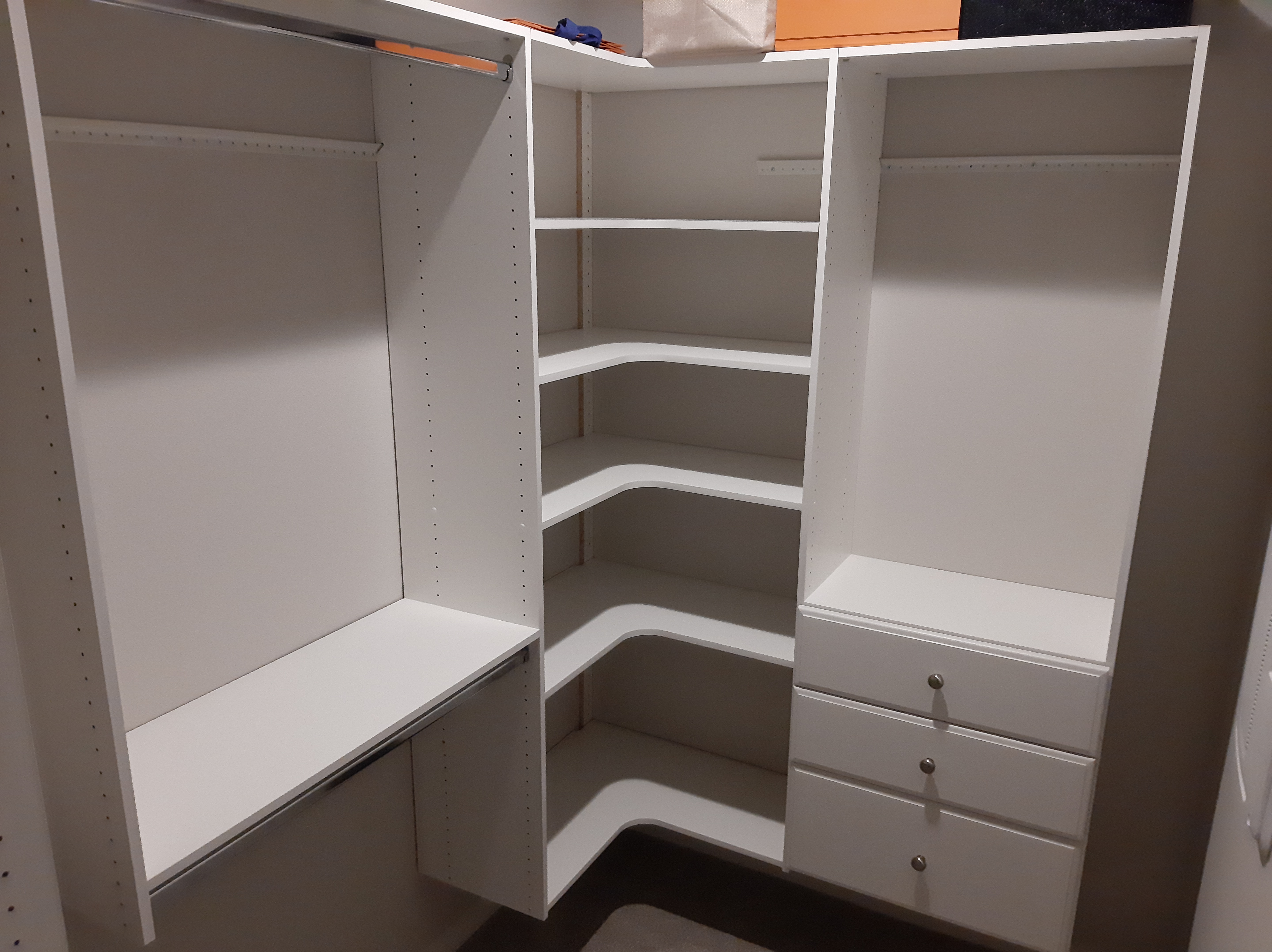 Corner closet with white built-in shelves and drawers installed, Seattle